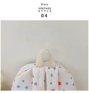 Close-up of cream backpack featuring colorful star patterns and durable canvas texture