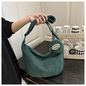 Detail view of dark green corduroy crescent shoulder bag with round fashion coin purse