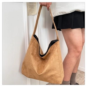 Detail of a large brown suede hobo tote bag featuring a wide shoulder strap and soft texture