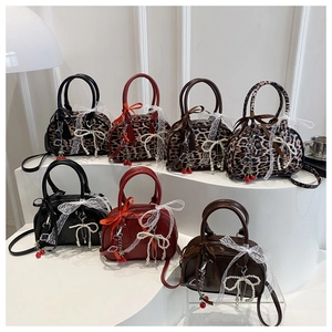 Detail view of colorful Boston bags featuring lace bows, pearls, and cherry charms