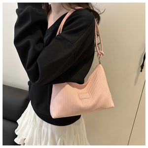 Sac à bandoulière plissé rose avec texture verticale et logo porté par un mannequin