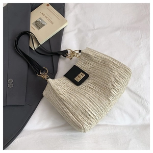 Detailed close-up of woven tote bag featuring black leather trim and gold twist lock closure