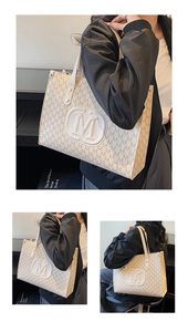 Detail view of large beige tote bag with M-letter print and central embossed logo