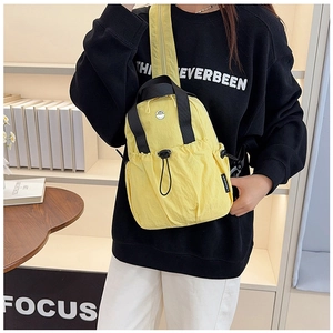 Detail of yellow nylon travel backpack with front drawstring pocket and black handle