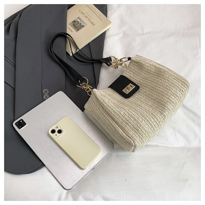 Detailed macro view of cream V-weave straw bag with black leather flap and gold twist lock