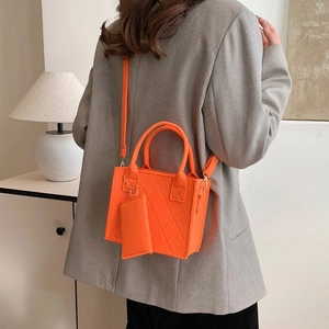 Detail einer gesteppten Filzumhängetasche in Orange mit passender Münzbörse am Model