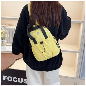 Detailed back view of a bright yellow nylon crossbody bag on a female model