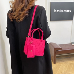Detailaufnahme der pinkfarbenen gesteppten Filztasche mit Minianhänger auf schwarzem Mantel