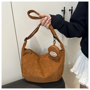 Detail view of brown corduroy crescent bag featuring a mini pouch and fashion text
