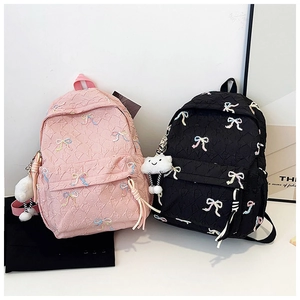 Detail of pink and black striped backpacks with bow embroidery and cloud charms