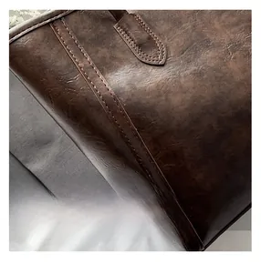 Detailed close-up of brown vintage faux leather texture and reinforced double stitching on tote bag