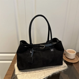 Large black suede tote bag with long handles and metal buckle in a vintage minimalist style