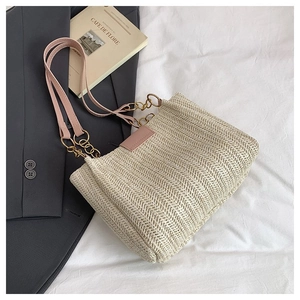 Detail of beige woven tote bag with pink leather strap and gold chain link hardware