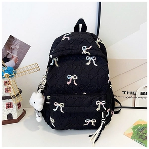 Detail of black quilted backpack with colorful bow accents and soft cloud pendant charm