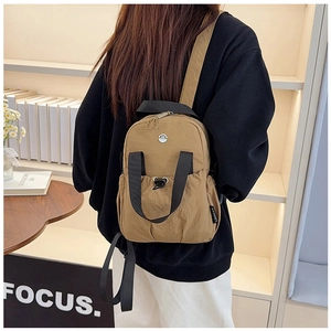 Close-up of camel nylon backpack with branded woven label and metal logo detail