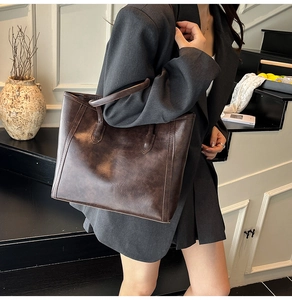 Macro view of vintage brown leather tote bag showing thick texture and sturdy handles