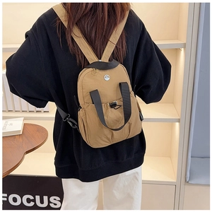 Detailed view of dark khaki nylon mini backpack with drawstring pocket and black straps
