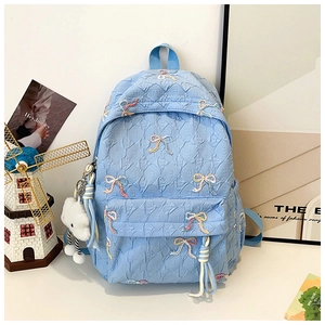 Detail of light blue quilted backpack featuring colorful bow embroidery and soft cloud charm