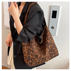 Detail of a large leopard print tote bag in suede texture styled with a black blazer