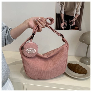 Pink corduroy crescent bag with small fashion pouch on a minimalist wooden table