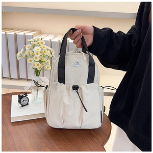 Detail of cream nylon backpack with black handles and drawstring pocket in a cozy setting