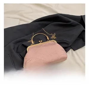Detailed macro view of pink textured evening bag with golden metal frame and circular handle