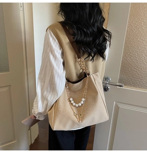 Detail of beige tote bag featuring pearl chain, gold hardware, and leather strap