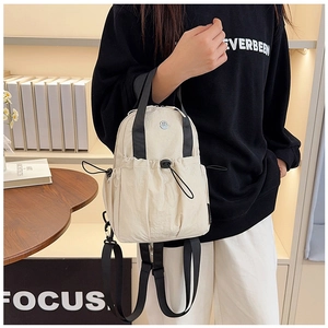 Detail of a lightweight cream nylon backpack with drawstring pocket and black straps