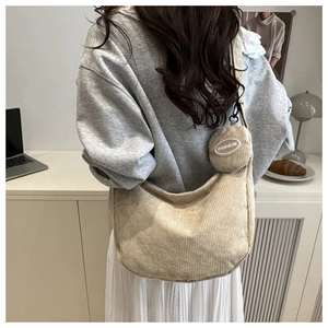 Detailed view of beige corduroy crescent bag with small round coin pouch attachment