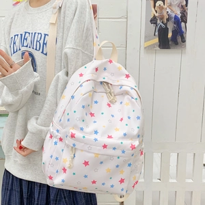 White canvas backpack with colorful star patterns shown on a model for casual school style
