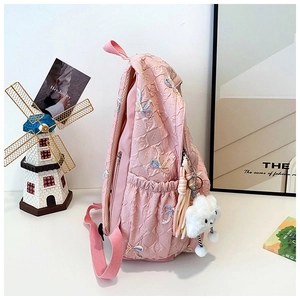 Pink backpack side view with embossed letters, colorful bows and cloud plush charm