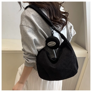 Detailed side view of black corduroy hobo bag with matching round mini coin purse