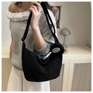 Detail of black corduroy shoulder bag with textured stripes and matching round coin purse