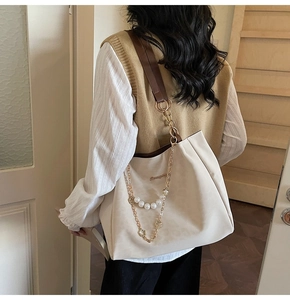 Detail of cream tote bag with pearl chain and floral pendant on matte leather