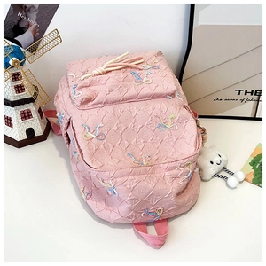 Detailed view of pink quilted backpack with colorful butterfly embroidery and cloud charm