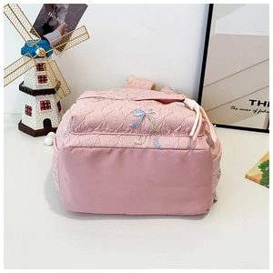 Detail of pink quilted school backpack with colorful embroidered butterfly bow accents