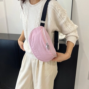 Détail du sac bandoulière rose en nylon porté par un mannequin avec sangle réglable