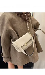 Detail of off-white crossbody bag featuring a unique golden peanut-shaped metal buckle