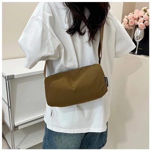 Detail of adjustable wide shoulder strap and brand logo on khaki nylon crossbody bag