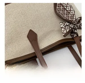 Dettaglio della borsa tote con cuciture precise e manico in pelle con sciarpa decorativa di seta