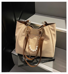 Detail of Sunnycity tote bag showing pearl chain and metal logo on beige faux leather
