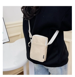 Adjustable beige corduroy crossbody phone bag worn by a model in a minimalist room