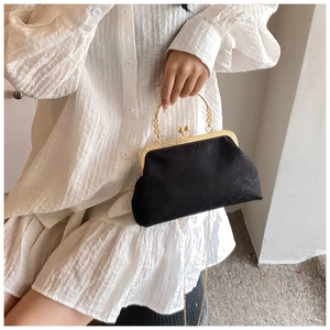 Detail of vintage black lace shell bag with ornate gold handle and metal chain strap