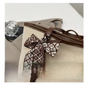 Dettaglio della borsa tote intrecciata con manici in pelle e foulard decorativo in seta