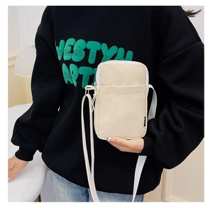 Detail of cream nylon crossbody phone bag showing waterproof texture and zipper pocket