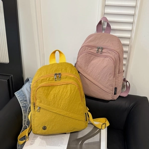 Minimalist nylon backpacks in yellow and lilac colors on a leather chair for daily commute