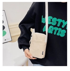 Close-up of beige corduroy crossbody phone bag with adjustable strap and sport label