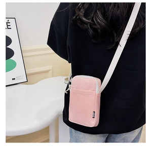 Detail of pink nylon crossbody phone bag with white zipper and sport tag in casual style