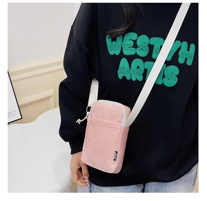 Close-up of pink nylon crossbody bag with white adjustable strap and SPORT label