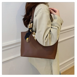 Brown leather tote bag with elegant printed scarf detail shown on a model's shoulder